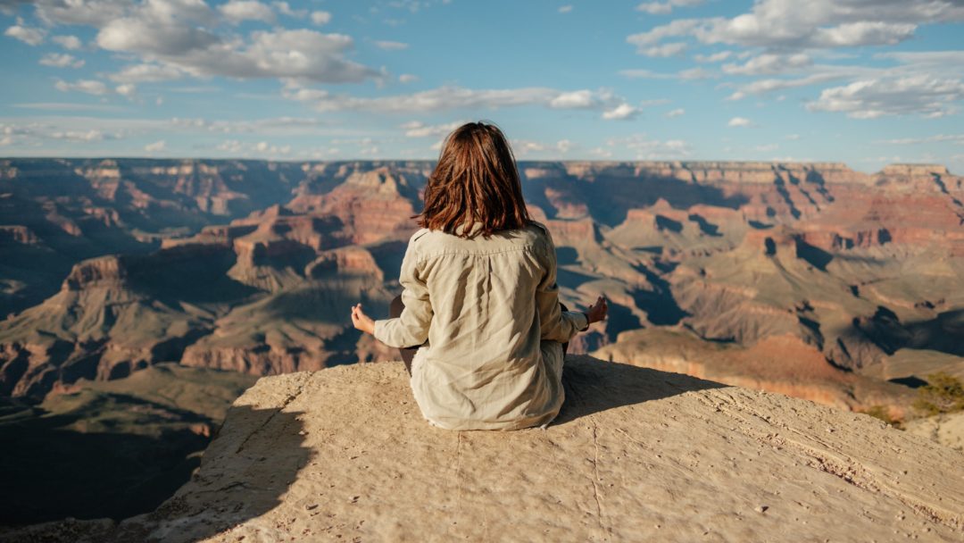 A woman sitting at the edge of the Grand Canyon.