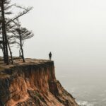 A human standing on a cliff edge by the sea.